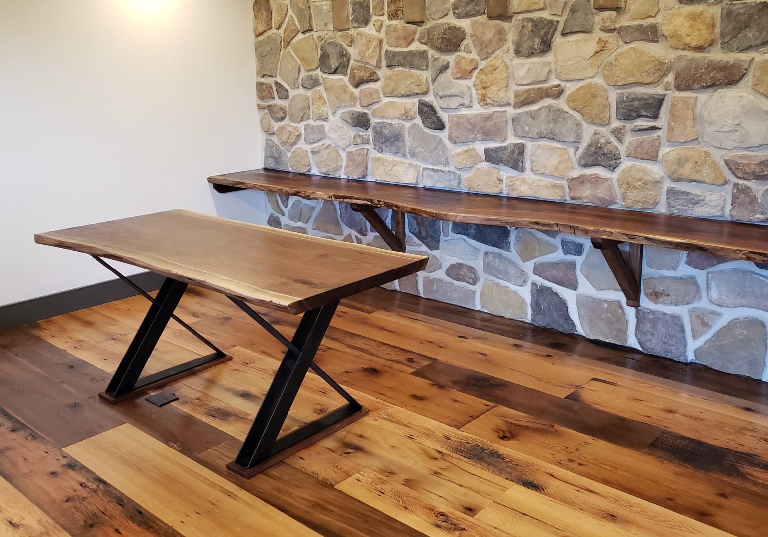 Wooden table and bench against stone wall.
